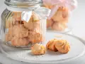 Biscuits sablés dans des bocaux en verre décorés de rubans blancs et roses, parfaits pour un dessert pique-nique.