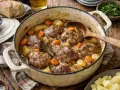 Un plat mijoté de joue de porc au cidre, avec pommes de terre et carottes, servi dans une cocotte en fonte.