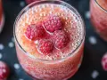 Verre de soupe de champagne pétillante, garni de framboises givrées. Un délice fruité et festif.
