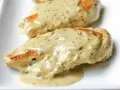 Deux morceaux de poulet à la crème, nappés d'une sauce onctueuse aux herbes, sur une assiette blanche.