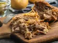 Un délicieux effiloché de porc, tendre et savoureux, prêt à être dégusté sur une planche en bois.