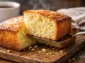 Un délicieux gâteau nature, encore chaud, est servi sur une planche en bois. La vapeur s'en dégage, invitant à la dégustation.
