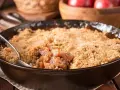 Un délice de pâte à crumble croustillante sur un lit de fruits fondants, servi dans une poêle en fonte.