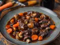 Un plat de boeuf bourguignon cookeo, avec des morceaux de viande tendres, des champignons et des carottes, nappés d'une sauce riche.