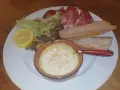 Un plat avec un fromage fondant, des tranches de jambon, de la salade, des noix, une tranche de citron et du pain. Une idée de recette amuse bouche facile sans cuisson.