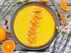Une délicieuse tarte à l'orange, garnie de fines tranches d'orange, d'amandes effilées et de petites fleurs bleues. Un régal visuel et gustatif.