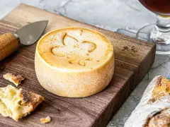 Un fromage rond, marqué d'une fleur de lys, prêt à être dégusté. Une invitation à découvrir comment faire du fromage.