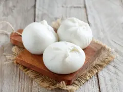Trois boules de burrata crémeuse sur une planche en bois, parfaites pour comprendre la différence burrata et mozzarella.