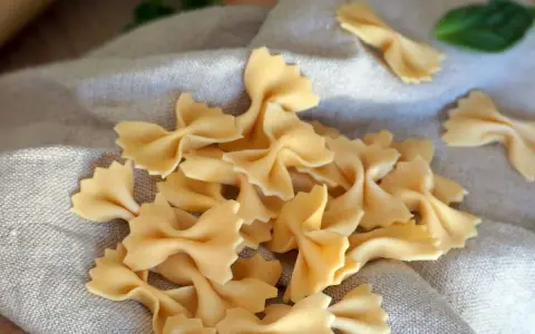 Farfalles fraîches, prêtes pour une délicieuse recette pâte maison. Une feuille de basilic ajoute une touche de couleur.