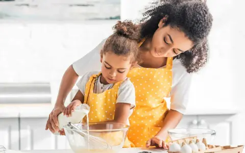 Une mère et sa fille préparent une recette, la petite verse du lait ribot dans un bol.