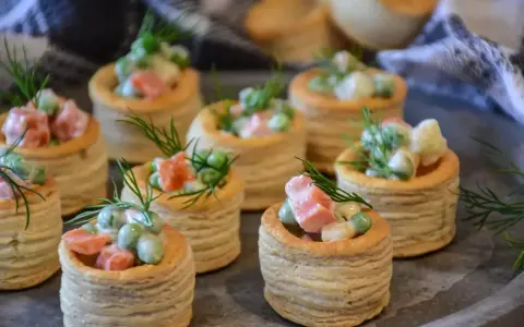 Petits bouchées à la reine, garnies d'une salade crémeuse de petits pois, carottes et jambon, décorées d'aneth. Parfaites pour un apéritif gourmand.