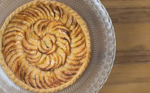 Tarte aux pommes dorée sur un plat en verre, parfaite pour une recette gâteau avec pâte feuilletée facile.