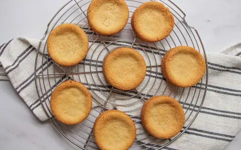 Huit palets bretons dorés, prêts à être garnir, refroidissent sur une grille.