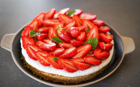 Tarte aux fraises mascarpone, une gourmandise estivale recouverte de fruits rouges frais et de feuilles de menthe.