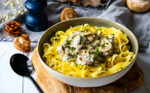 Un plat de pâtes tagliatelles garni d'une onctueuse sauce pour pâtes farcies aux champignons, parsemé de persil frais.