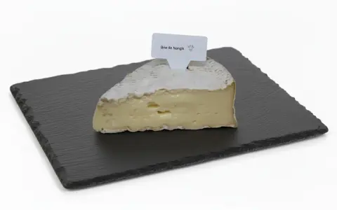 Une part de brie de Nangis, crémeux et à la croûte fleurie, repose sur une ardoise.