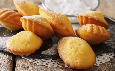 Des madeleines dorées, saupoudrées de sucre glace, prêtes à être dégustées. Une invitation à la recette madeleine parfaite.