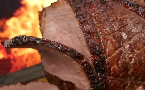 Un enchaud de porc juteux, rôti à la perfection, avec une croûte caramélisée et des flammes dans l'arrière-plan.