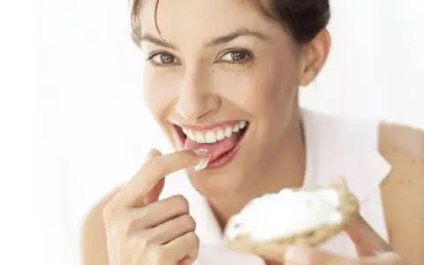 Une femme savoure une bouchée de pain avec de la saint agur crème enceinte, un sourire aux lèvres.