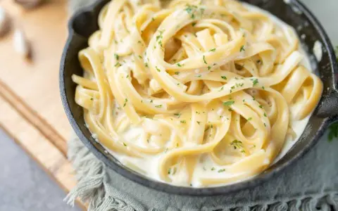 Fettuccine crémeux enrobé d'une onctueuse sauce fromage blanc, parsemé de persil frais. Un délice réconfortant.
