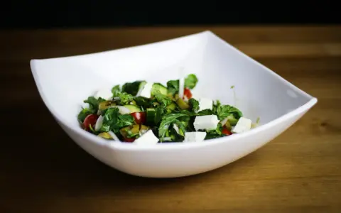 Salade fraîche et colorée avec des cubes de fromage pour salade, tomates cerises, concombres et olives vertes.