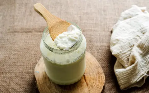 Une cuillère en bois prélève du lait fermenté d'un bocal. Idéal pour savoir que faire avec du lait fermenté.