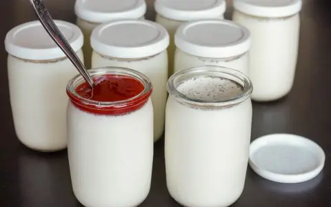 Yaourts maison préparés avec une yaourtière, certains garnis de confiture de fruits rouges. Une recette simple pour un yaourt maison.