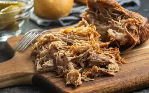 Un délicieux effiloché de porc, tendre et savoureux, prêt à être dégusté sur une planche en bois.
