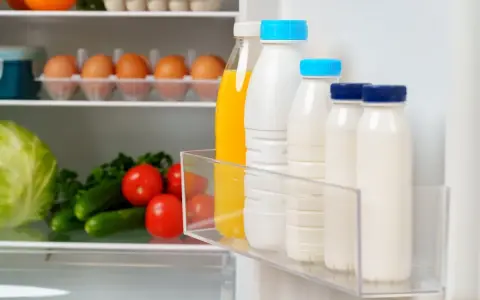 Bouteilles de lait et jus pour une bonne conservation lait frigo. Légumes frais sur l'étagère du bas.