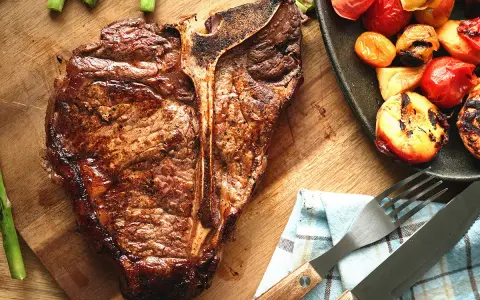 Un succulent côte de bœuf grillé, accompagné d'asperges et de tomates rôties, prêt à être dégusté.