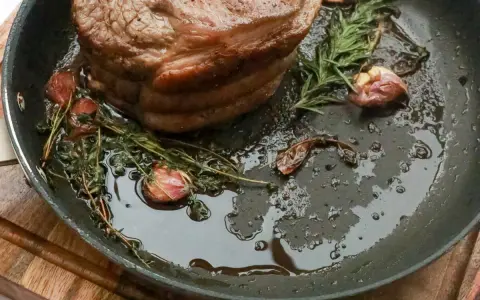 Rouelle de porc au barbecue, rôtie dans une poêle avec de l'ail et des herbes aromatiques, prête à être dégustée.