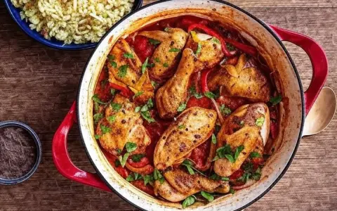Un plat mijoté de poulet basquaise de ma grand-mère, avec des morceaux de poulet dorés, des poivrons et une sauce tomate savoureuse, garni de persil frais.