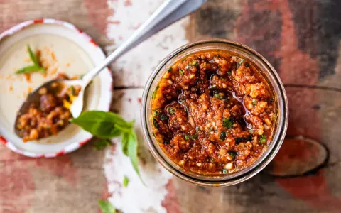 Un pot de pesto rosso maison, prêt à être dégusté. Une recette simple et savoureuse pour relever vos plats.