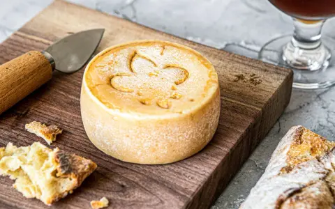 Un fromage rond, marqué d'une fleur de lys, prêt à être dégusté. Une invitation à découvrir comment faire du fromage.