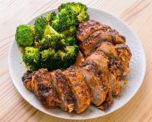 Filet mignon air fryer, tranché et servi avec du brocoli rôti. Un repas sain et savoureux.