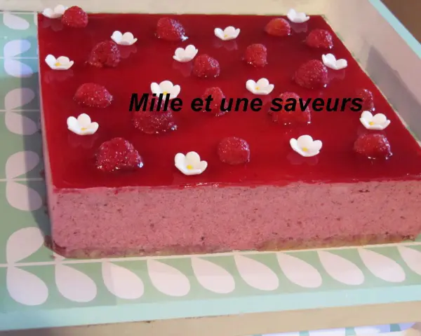 Un délicieux bavarois fruits rouges, orné de framboises fraîches et de petites fleurs blanches, promet une explosion de saveurs.