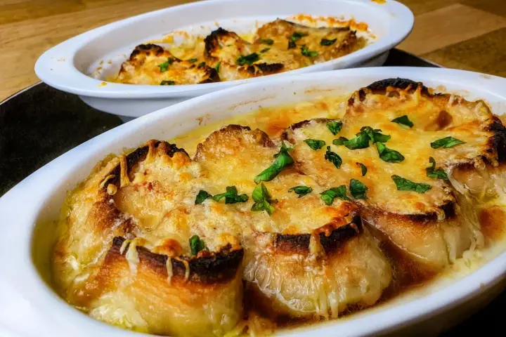 Deux gratins de soupe à l'oignon, dorés et gratinés, prêts à être dégustés. Une recette réconfortante.