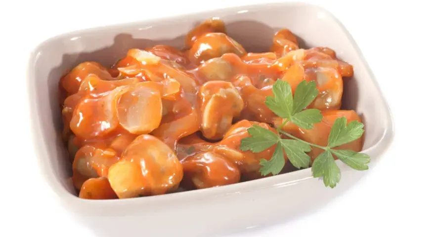 Champignons à la grecque, tendres et savoureux, baignant dans une sauce tomate onctueuse, garnie d'une touche de persil frais.
