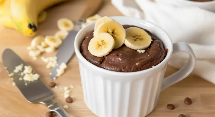 Un délicieux mug cake banane au chocolat, garni de rondelles de banane fraîche. Parfait pour une envie gourmande rapide.