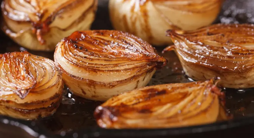 Moitiés d'oignons caramélisés, dorés et juteux, cuisant dans une poêle.