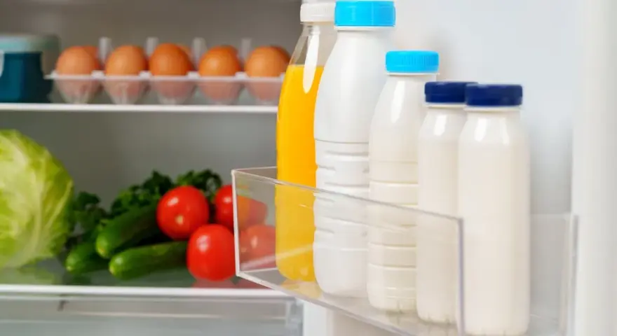Bouteilles de lait et jus pour une bonne conservation lait frigo. Légumes frais sur l'étagère du bas.