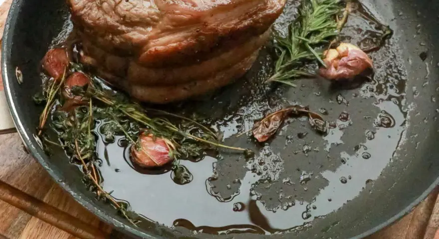 Rouelle de porc au barbecue, rôtie dans une poêle avec de l'ail et des herbes aromatiques, prête à être dégustée.