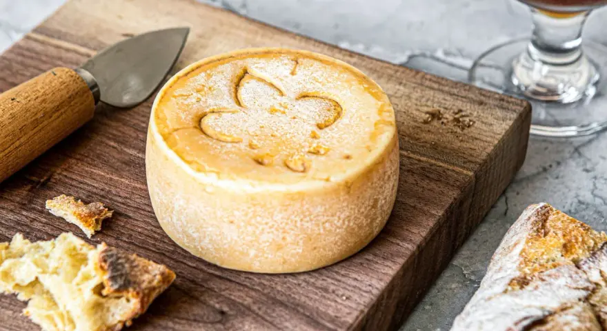 Un fromage rond, marqué d'une fleur de lys, prêt à être dégusté. Une invitation à découvrir comment faire du fromage.