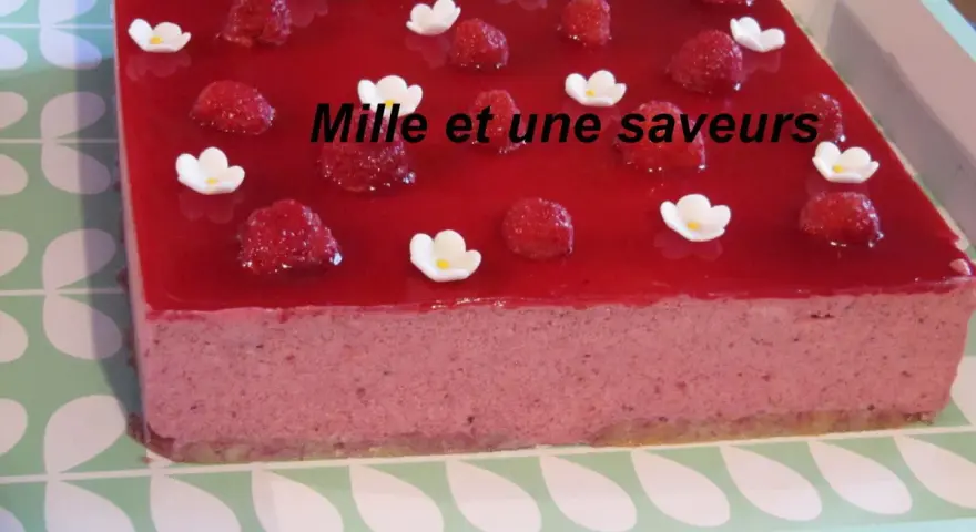 Un délicieux bavarois fruits rouges, orné de framboises fraîches et de petites fleurs blanches, promet une explosion de saveurs.