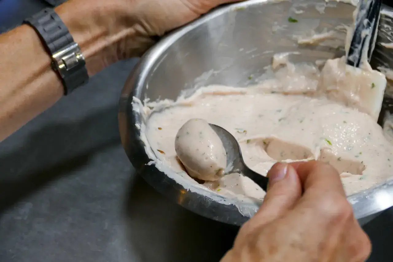 Une cuillère prélève une quenelle de glace crémeuse dans un bol.