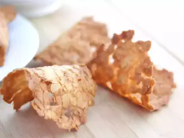 Trois tuiles aux amandes croustillantes, dorées et délicates, posées sur une planche en bois.