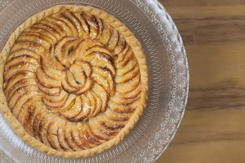 Tarte aux pommes dorée sur un plat en verre, parfaite pour une recette gâteau avec pâte feuilletée facile.