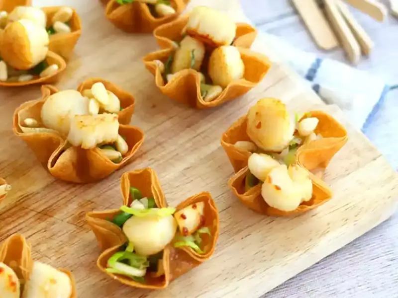 Bouchées à la reine aux Saint-Jacques, garnies d'une béchamel crémeuse et de pignons. Un délice croustillant.